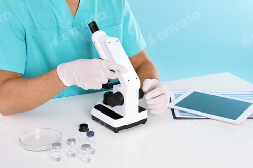 Preview: Male doctor using microscope at table, closeup. Medical object
