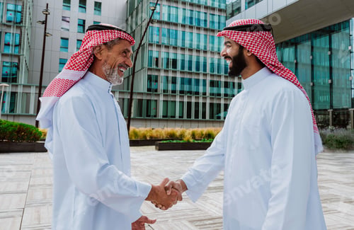 Preview: Saudi businessmen shaking hands finalizing deal outdoors