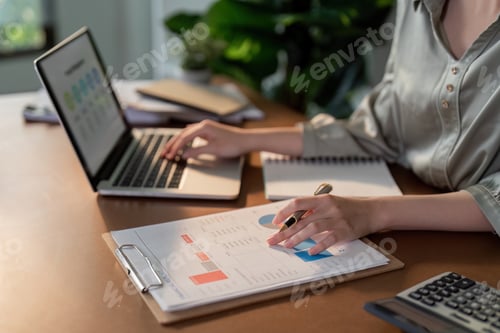 Empresaria usando una computadora portátil y trabajando en la oficina con el documento de la calculadora en el escritorio, haciendo