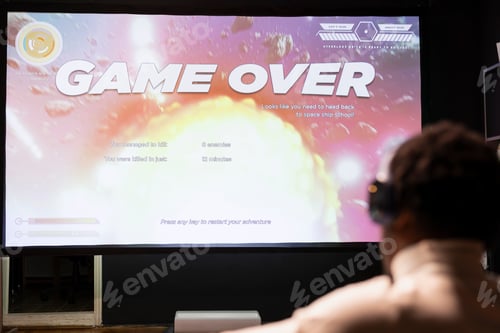 Preview: Gamer wearing headphones upset at seeing game over message on widescreen TV