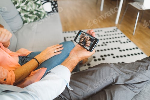 Preview: Senior couple resting on the couch while talking to family over video chat on the phone