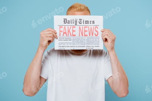 Preview: man holding newspaper with fake news in front of face, isolated on blue
