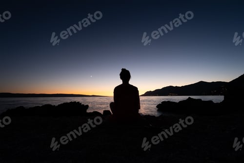 Preview: Silhouette girl on the sky background during sunset. Yoga and meditation.