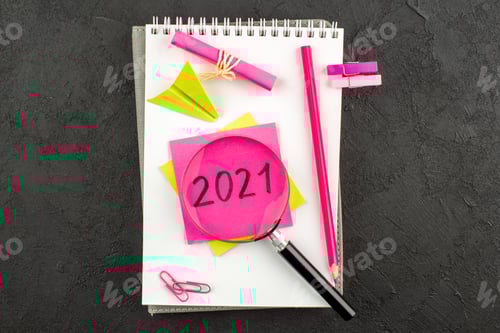 Visualização: vista superior: lápis rosa lupa on escrito em nota adesiva em caderno espiral em fundo escuro