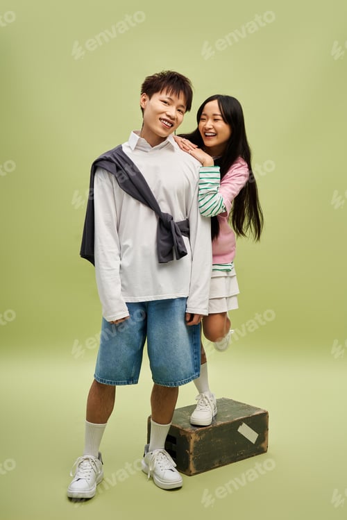 Preview: Stylish couple sharing laughter in a playful moment amidst a pastel backdrop