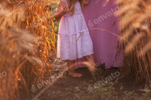 Preview: On the black wet ground among the spikelets of wheat stand the dirty feet of the daughter mother