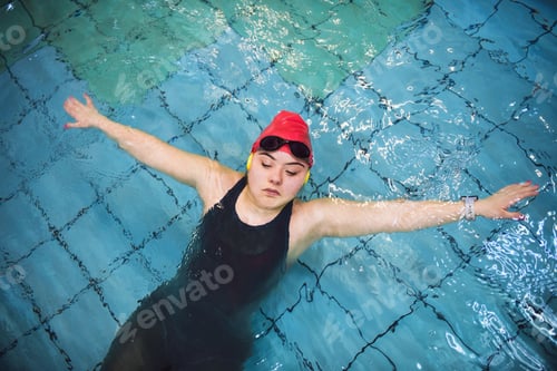 Preview: Top view of young woman with Down syndrome swimming in swimming pool