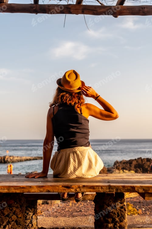 Preview: woman at sunset looking at the sea on the beach of Tacoron on El Hierro, Canary Islands, in summer