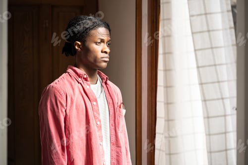 Preview: Depressed African guy looking out of window thinking about suicide, feeling apathy