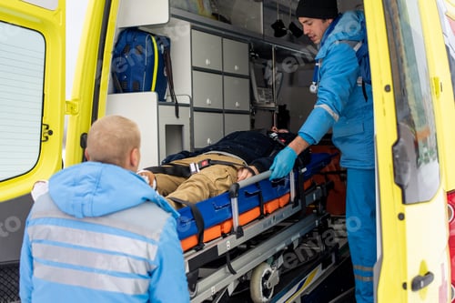 Preview: Paramedics in uniform pushing stretcher with unconscious man into ambulance car