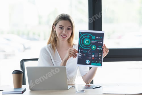 Preview: Smiling businesswoman showing paper near gadgets and coffee to go in office
