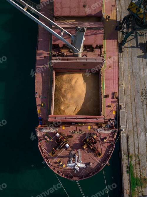 Preview: cargo ship or bulk carrier loaded to the brim with grain is preparing for departure, working sailors