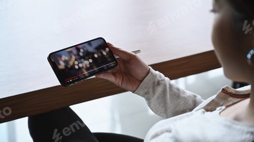 Preview: Close up view young woman watching online movie with smart phone.