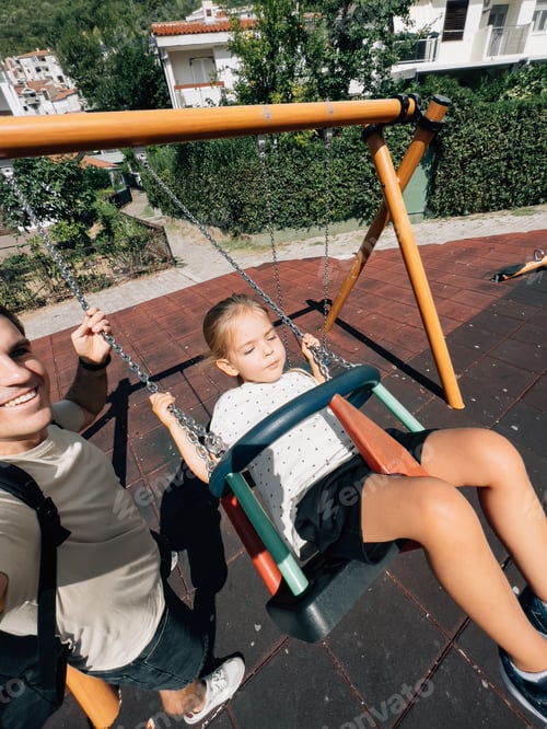 Preview: Dad swings a little girl on a chain swing at the playground