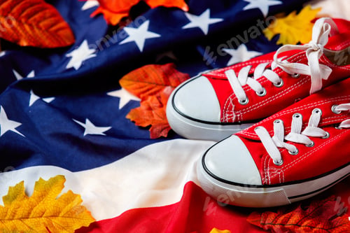 Preview: Red gumshoes with autumn leaves on USA flag background. Top view