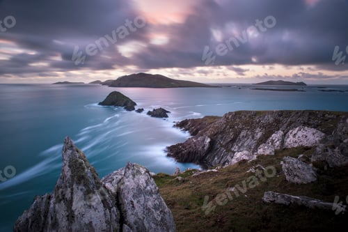 Preview: Sunset over a serene coastal landscape with rocky cliffs and calm sea