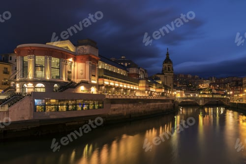 Preview: City riverbank with glowing buildings in evening