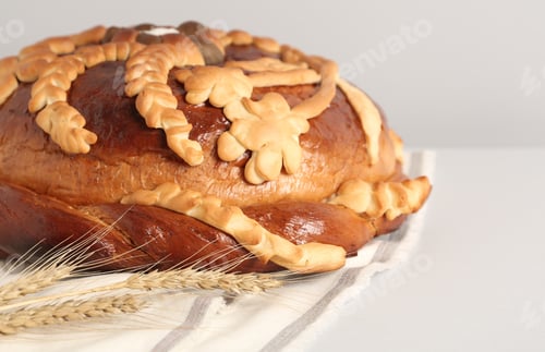 Preview: Korovai with wheat spikes on white table, closeup. Ukrainian bread and salt welcoming tradition