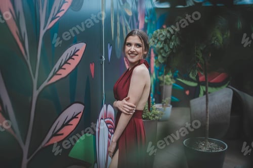 Preview: Cheerful sexy Caucasian woman in a red backless gown posing outdoors