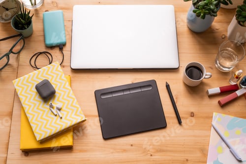 Preview: Notebooks with cordless earphones, folded laptop, pad with stylus, etc on table