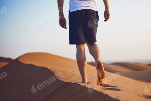 Preview: Young man walking on top of sand dune. Wahiba Sands in Oman.