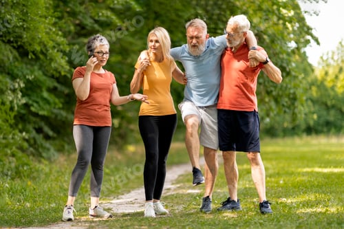 Preview: Senior man having leg injury during group training with friends outdoors