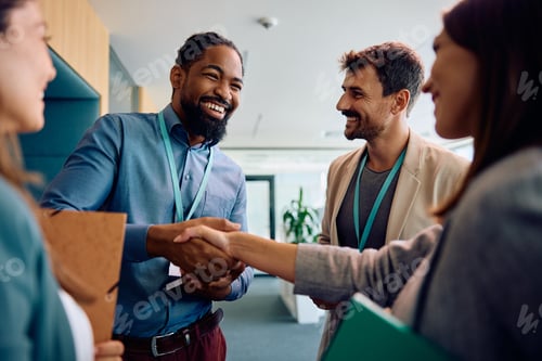 Preview: Cheerful black businessman greeting his colleagues in the office.