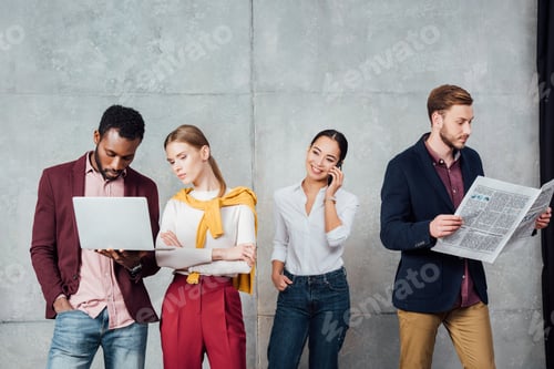 Preview: multiethnic casual businesspeople using digital devices and reading newspaper in waiting hall