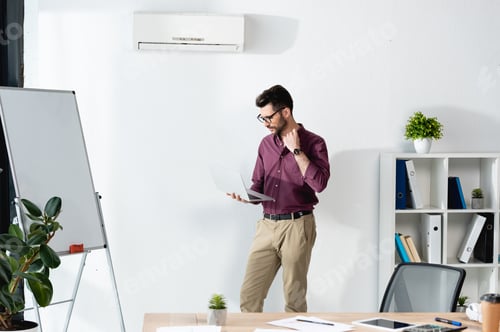 Preview: Man Holding Laptop Computer in Office Setting