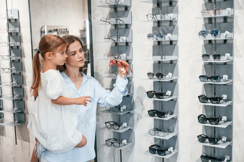 Preview: Mother and daughter. Woman and girl is in the glasses store choosing eyewear together