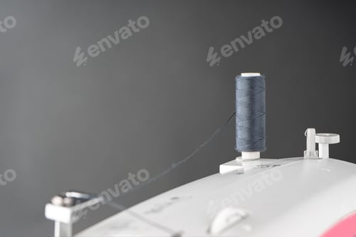 Preview: Spool Of Gray Sewing Thread Stands On Top Of A White Modern Sewing Machine