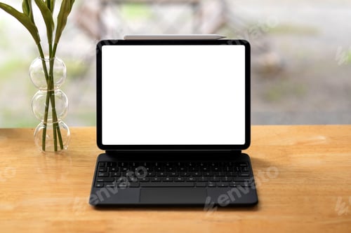 Preview: Tablet blank white screen with a flower vase placed on the wooden office table.