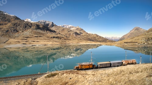 Preview: Small freight train on rails near a high mountain lake