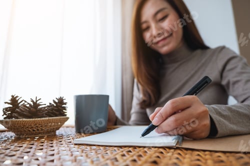 Preview: A beautiful young asian woman writing on notebook while study at home