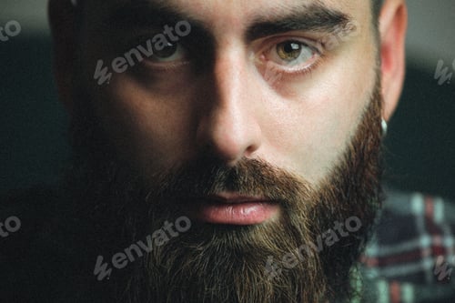 Preview: Young hipster man with a beard and a plaid shirt with shadows and copy space, portrait