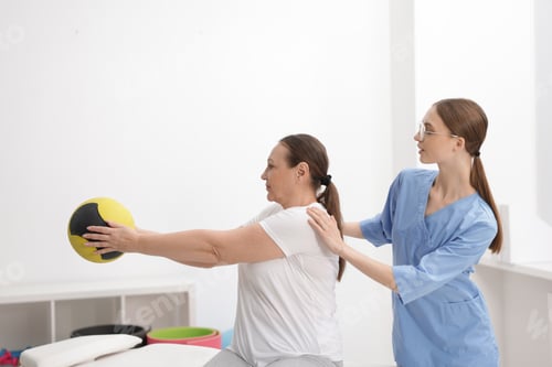 Preview: Doctor and patient exercising with medicine ball in clinic