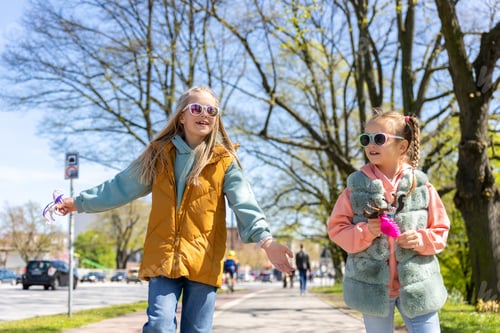 Preview: Two cute little children girlfriends enjoy fun talk walking in Hamburg city street park on sunny day