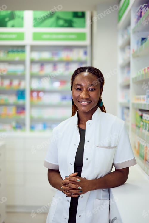 Preview: Smiling Pharmacist Standing in Pharmacy Interior with Shelves in Background