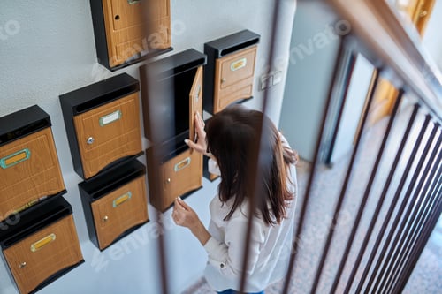 Preview: Woman checking mailboxes inside an apartment building
