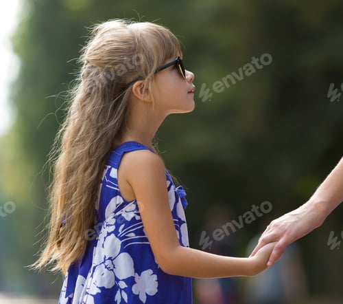 Preview: Back view of young blond long-haired attractive woman and small child girl holding hands outdoors