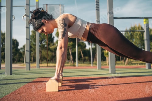 Preview: Young calisthenic woman practicing push-ups outdoors