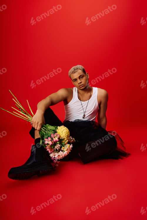 Preview: Young stylish man showcases modern fashion in vibrant red studio setting