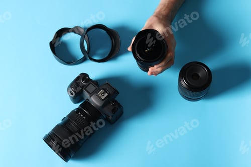 Preview: Photographer with professional camera and equipment on light blue background, top view