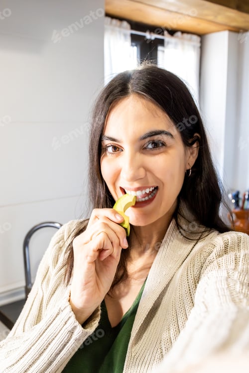 Preview: Smiling woman eating fresh avocado in kitchen. Lifestyle.