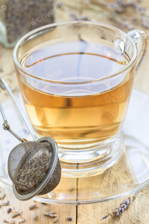 Preview: Healthy herbal lavender tea in a glass cup with lavender flowers on background, vertical