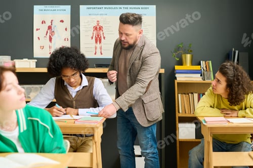 Preview: Mature male teacher of anatomy checking notes of highschool student