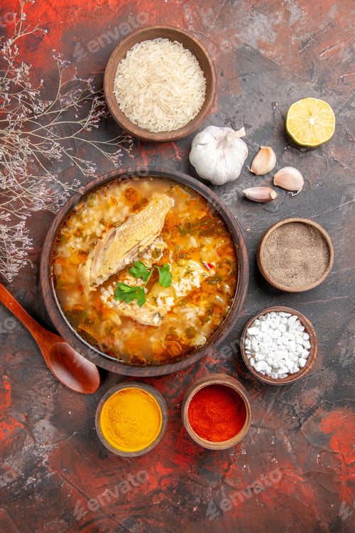 Preview: top view homemade chicken and rice soup in a bowl wooden spoon bowl of rice garlic slice of lemon
