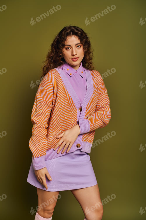 Preview: Stylish young woman in vibrant outfit poses confidently against a green background