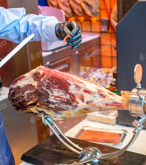 Preview: a man is cutting a piece of Iberian Ham with a knife