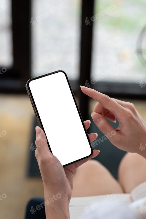 Preview: business woman hands sitting at the office using a smartphone with a blank white screen.